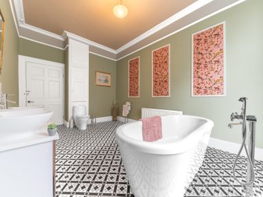A bathroom with a bathtub a toilet a sink and framed art on walls at 8 Corkickle in Whitehaven