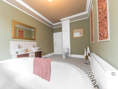 A bathroom with a white freestanding tub and pink towel a double sink with mirror toilet and towel stand at 8 Corkickle Whitehaven