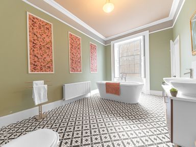 A bathroom with a freestanding bathtub a towel rack a double sink a toilet and framed artwork on the walls at 8 Corkickle in Whitehaven