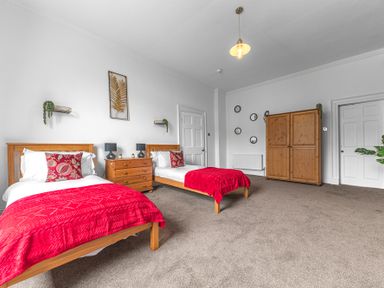 A bedroom with two single beds wooden furniture and red blankets at 8 Corkickle in Whitehaven