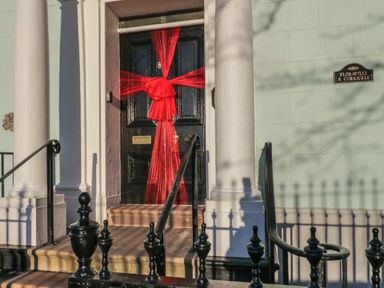 A black front door with a large red bow between two white columns at Floraville 8 Corkickle in Whitehaven