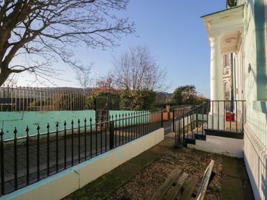 A front yard with a paved pathway black metal fences a bench and steps leading to a house at 8 Corkickle in Whitehaven