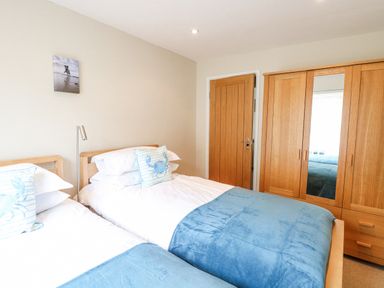 A bedroom with two single beds blue blankets wooden wardrobe and a door at Crab Corner in Wells-Next-The-Sea