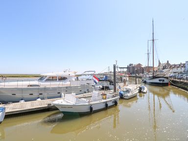 A harbor with multiple docked boats and buildings along the waterfront at Crab Corner in Wells-Next-The-Sea