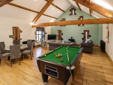 A room with a pool table a dining table with chairs and a sitting area with sofas and a TV at The Barn by Lyons in Talybont near Barmouth