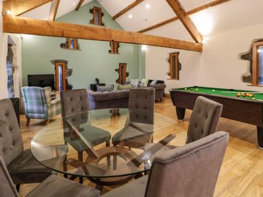 A room with a glass dining table surrounded by chairs a pool table sofas and a television at The Barn by Lyons in Talybont near Barmouth