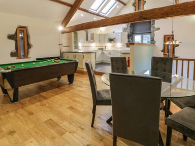 A room with a pool table and a round glass dining table with chairs near a kitchen at The Barn by Lyons in Talybont near Barmouth