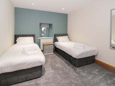 A bedroom with two single beds and a small bedside table at The Barn by Lyons in Talybont near Barmouth