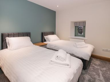 A bedroom with two single beds white bedding and a window at The Barn by Lyons Talybont near Barmouth