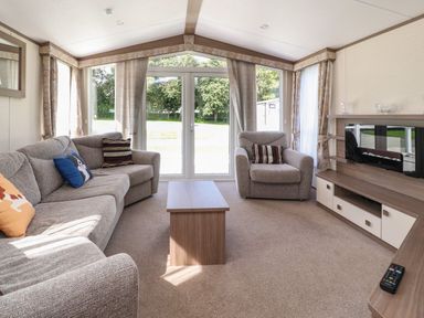 A living room with a sofa armchair coffee table and fireplace at 7 The Oaks in Long Preston near Hellifield