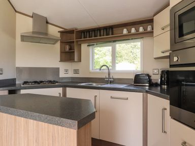 A kitchen with a stove sink toaster kettle microwave and cabinets at 7 The Oaks in Long Preston near Hellifield