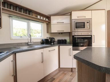 A kitchen with a sink under a window and countertop appliances at 7 The Oaks in Long Preston near Hellifield