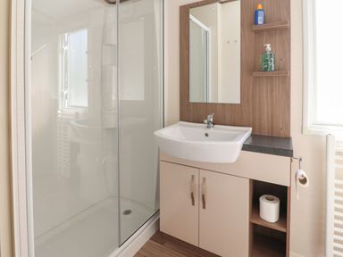 A bathroom with a shower cubicle and a sink with cabinet at 7 The Oaks in Long Preston near Hellifield