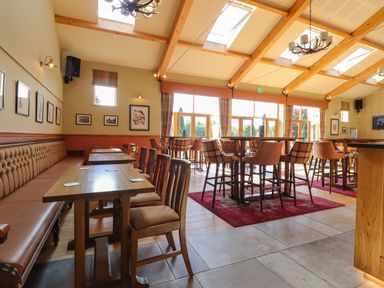 A dining area with wooden tables and chairs under a ceiling with skylights at 7 The Oaks in Long Preston near Hellifield