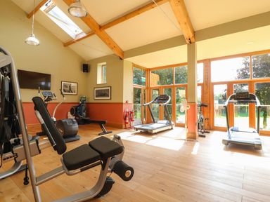 A gym with exercise machines treadmills and stationary bike with large windows at 7 The Oaks Long Preston near Hellifield