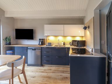 A kitchen with blue and white cabinets wooden countertop and dining table with chairs at Sir George Baker Cabin in Uplyme