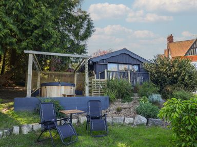 A garden with a hot tub and seating area at Sir George Baker Cabin in Uplyme