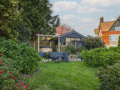 A garden with a hot tub and chairs at Sir George Baker Cabin in Uplyme