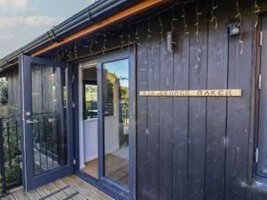 An entrance with glass doors and a sign at Sir George Baker Cabin in Uplyme