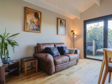 A living room with a sofa and paintings at Sir George Baker Cabin Uplyme