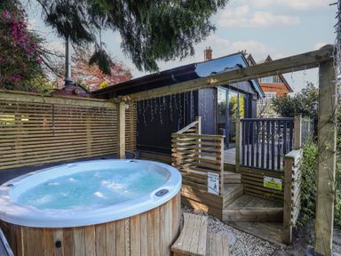 A hot tub next to wooden steps at Sir George Baker Cabin Uplyme