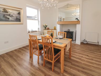 A dining room with wooden table and chairs a fireplace and a framed photograph on the wall at 18 Acklington Road Amble