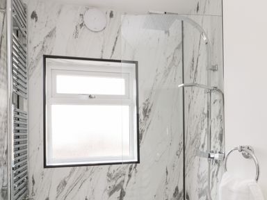 A bathroom with a window a showerhead and a towel ring with a towel at 18 Acklington Road in Amble