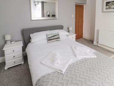 A bedroom with a bed two bedside tables and a mirror above the bed at 18 Acklington Road in Amble