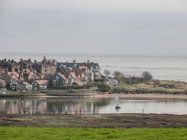 A coastal village with houses near a body of water and the sea in the background at 18 Acklington Road Amble