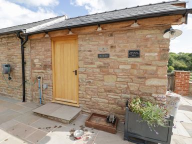 An outdoor area with a stone wall and a wooden door at Keepers Barn Bromyard