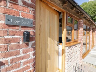 An entrance with a wooden door and sign at The Cow Shed in Bromyard