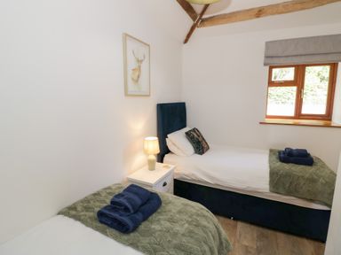 A bedroom with two single beds and a window at The Cow Shed in Bromyard