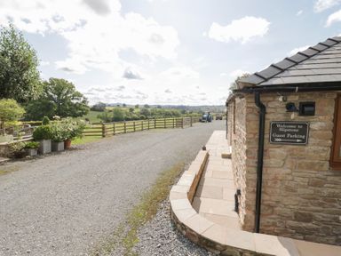 An outdoor area with a stone building and parking sign at The Cow Shed in Bromyard