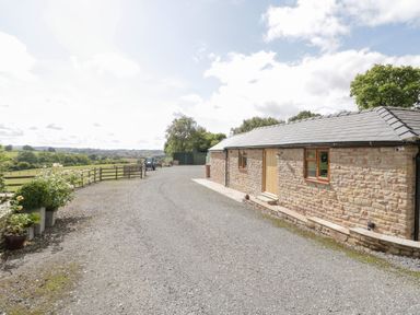 An outdoor area with a stone building and gravel pathway at The Cow Shed in Bromyard