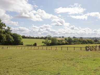 A field with trees and a fence at The Cow Shed in Bromyard