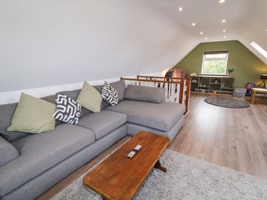 A living room with a grey sofa, wooden coffee table, bookshelf, and a window at Shore Road in Culdaff County Donegal