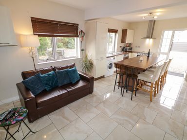 A kitchen and dining area with a brown leather sofa and a wooden dining table at Shore Road Culdaff County Donegal