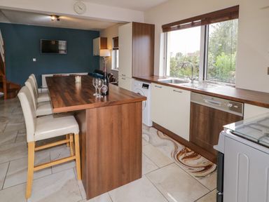 A kitchen with a wooden island and chairs and appliances by a window at Shore Road in Culdaff County Donegal