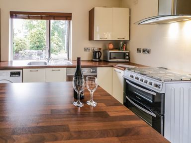 A kitchen with a wooden countertop bottle of wine and two wine glasses near a window at Shore Road Culdaff County Donegal