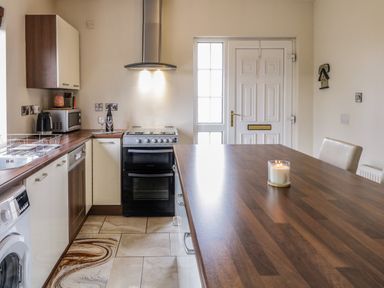 A kitchen with wooden countertops a white door a candle on the table and various kitchen appliances at Shore Road in Culdaff County Donegal
