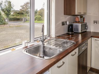 A kitchen sink with a dish rack on the countertop next to a microwave and electric kettle at Shore Road Culdaff County Donegal