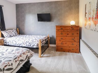 A bedroom with two beds a wooden chest of drawers and a TV mounted on the wall at Shore Road in Culdaff County Donegal