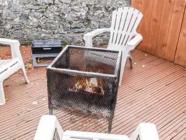 An outdoor seating area with white plastic chairs around a metal fire pit on a wooden deck at Shore Road in Culdaff County Donegal
