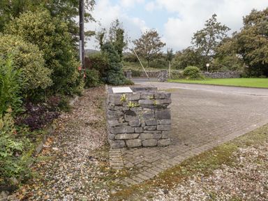 A stone structure on a pebble and brick driveway with bushes and trees in the background at Shore Road in Culdaff County Donegal
