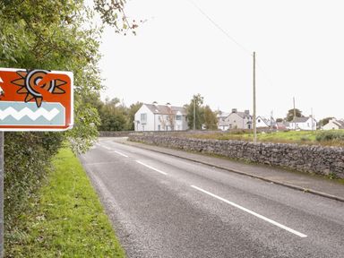 A road with a traffic sign and stone walls beside houses and green grass at Shore Road in Culdaff County Donegal