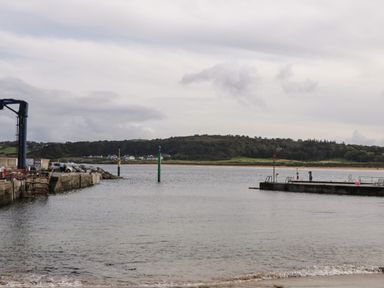 A view of a small harbor with piers on both sides and a hillside with houses in the background at Shore Road Culdaff County Donegal
