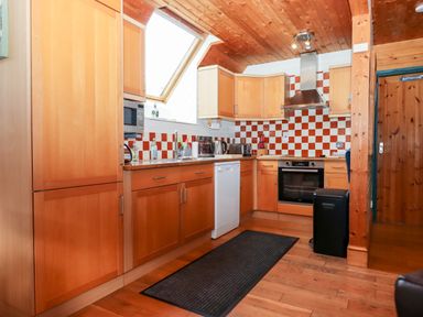 A kitchen with wooden cabinets a tiled backsplash a skylight window and appliances at Trout River Retreat Clifford Bridge near Moretonhampstead