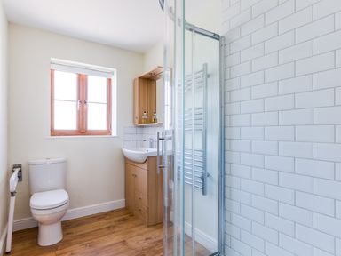 A bathroom with a toilet sink shower and wooden floor at Chy Pol in St Minver