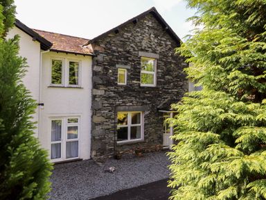 An exterior view of a house with stone and white walls surrounded by trees at Silver How in Ambleside