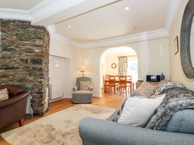 A living room with a stone fireplace chairs and a dining table visible through an archway at Silver How in Ambleside